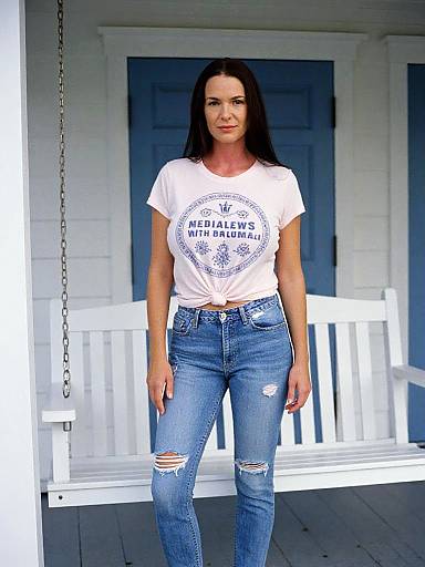 Casual Woman in Light Pink Graphic T-Shirt and Distressed Jeans on Porch