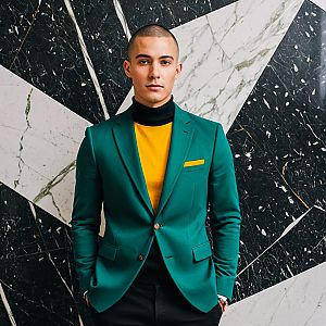 Confident Young Man in Teal Blazer Against Marble Wall