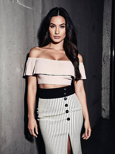 Stylish Woman in Off-Shoulder Top and Striped Skirt Against Concrete Wall