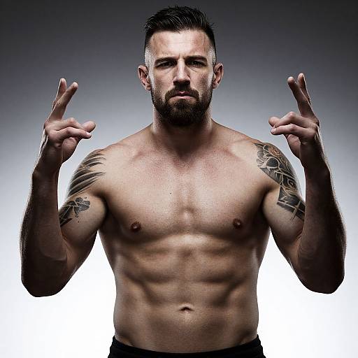 Muscular Shirtless Man with Tattoos and Beard Posing in Studio