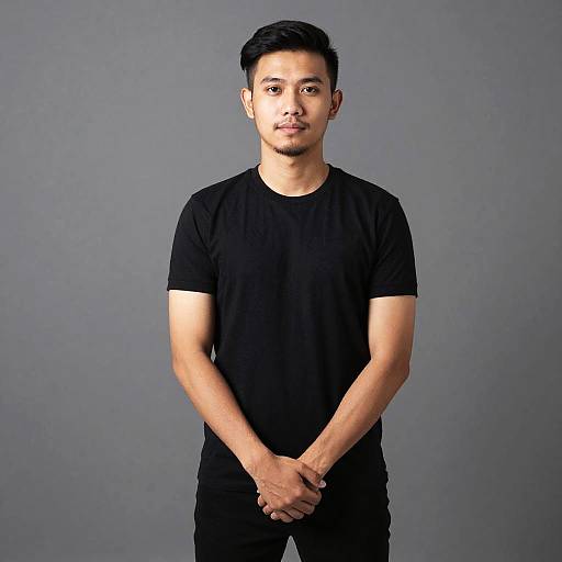 Young Man in Black T-Shirt Standing Confidently Against Gray Background