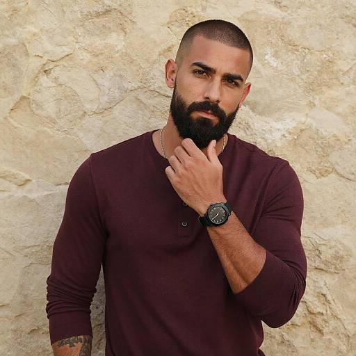 Bearded Man in Maroon Shirt with Watch Against Stone Wall