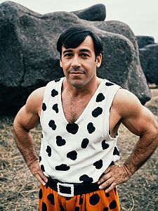 Man in Fred Flintstone Costume Photorealistic Humorous Cosplay Portrait