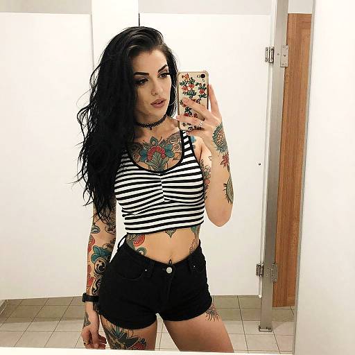Tattooed Woman Taking Mirror Selfie in Striped Crop Top and Black Shorts