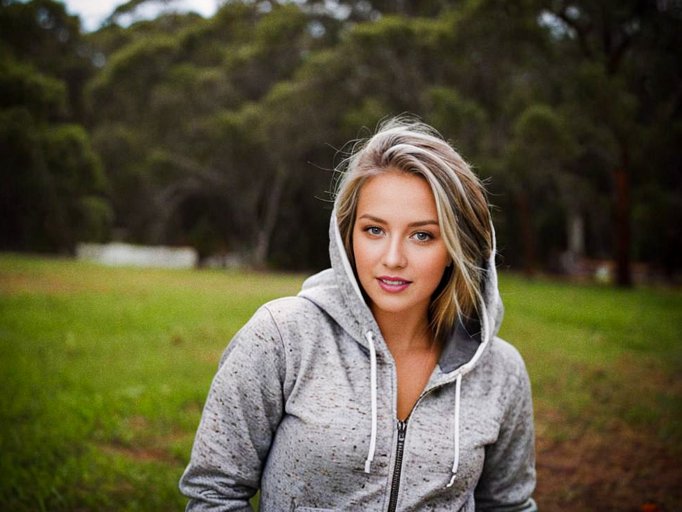 Confident Woman in Gray Hoodie in Green Landscape