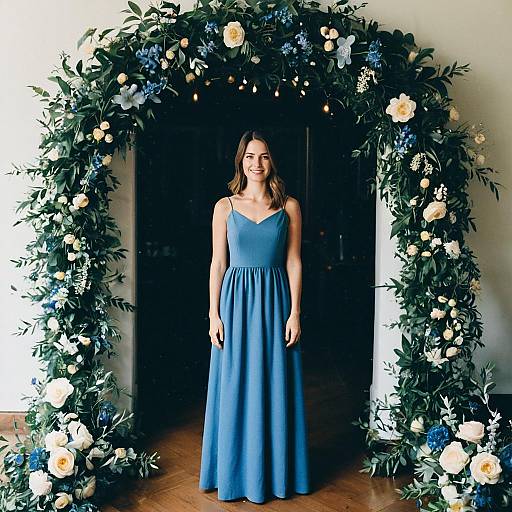 Woman in Simple Blue Gown Standing Under Floral Arch at Birthday Party