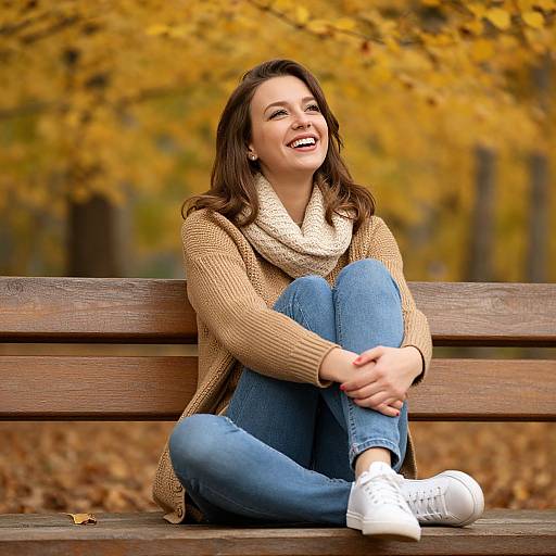 Happy Woman Sitting on Bench in Autumn Park with Cozy Sweater and Scarf