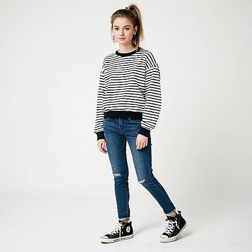 Young Woman in Casual Striped Sweater and Jeans on White Background
