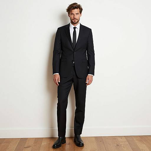 Man Wearing Classic Black Suit with Tie Standing Indoors