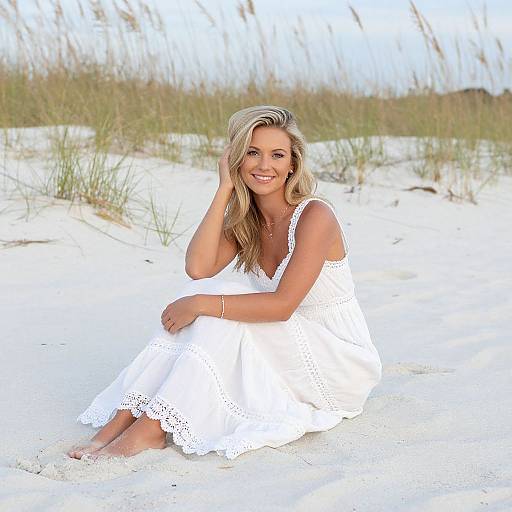 Woman in White Dress Sitting on Beach Sand Near Grass