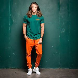 Confident Young Man in Streetwear Against Green Wall