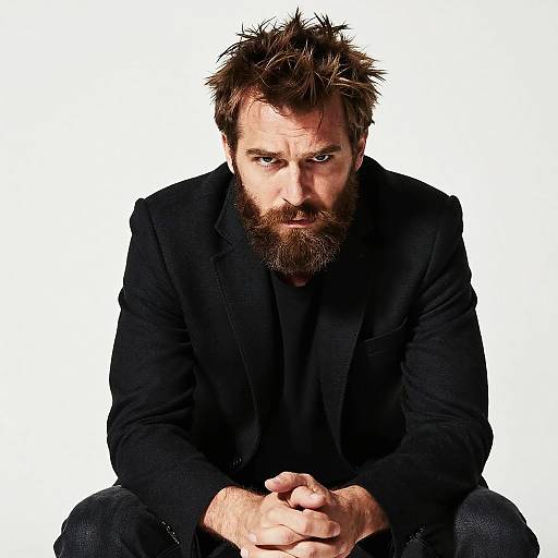 Bearded Man in Black Blazer with Intense Gaze Sitting