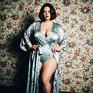Confident Woman in Floral Satin Robe Against Vintage Floral Wallpaper