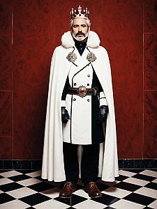 Regal Man in White Fur-Trimmed Cloak and Crown Standing on Checkered Floor