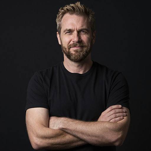 Confident Man with Beard in Black T-Shirt Against Dark Background
