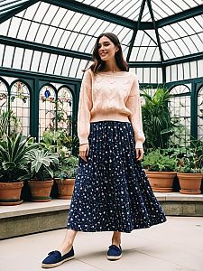 Woman in Pink Sweater and Floral Skirt in Greenhouse with Plants