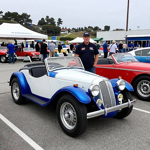 Photograph of a classic blue-and-white convertible car with chrome details, parked in a car show, next to a red classic car, with a uniform