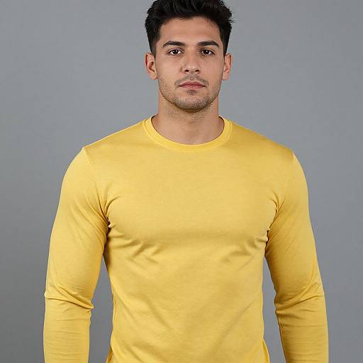 Photograph of a young man with short, dark hair, light brown skin, and stubble, wearing a bright yellow, long-sleeve shirt