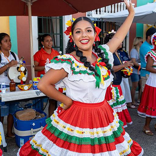 Photograph of a smiling Latina woman with dark hair in braids, wearing a colorful Mexican dress, posing with one arm raised at a festive outdoor event