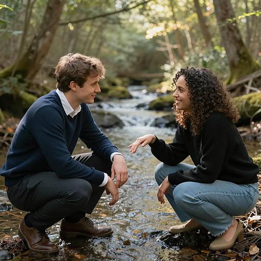 Couple crouching by a forest stream