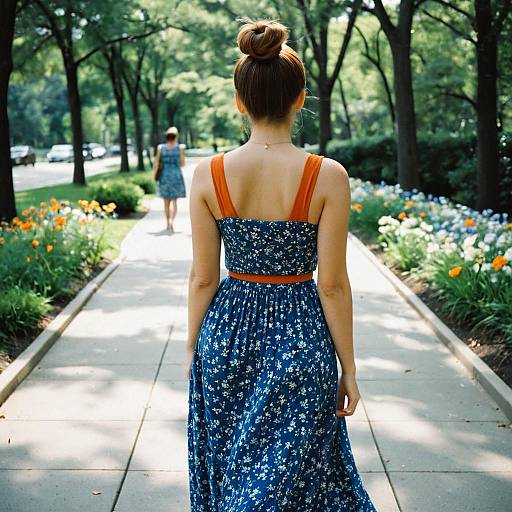 Young Woman in Blue Floral Dress Walking in Park