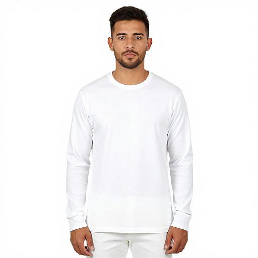 Photograph of a bearded man with short black hair, wearing a plain white long-sleeve shirt and white pants, standing against a plain white