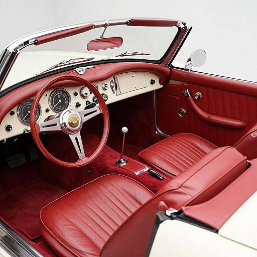 Photograph of a vintage car interior with red leather seats, matching red steering wheel, white dashboard, and chrome accents.