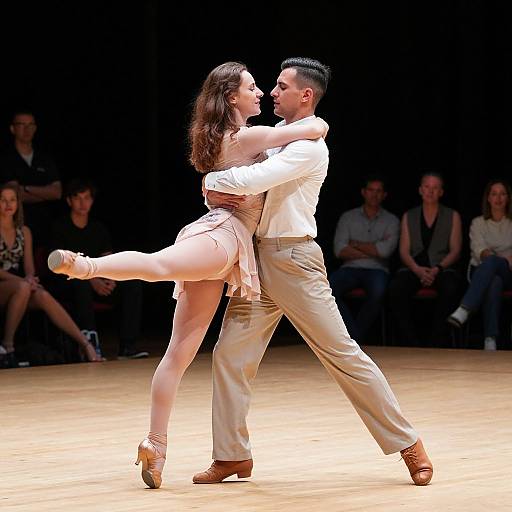 Photograph of a passionate ballroom dance couple in white attire, mid-spin, on a wooden stage with an audience in the dark background.