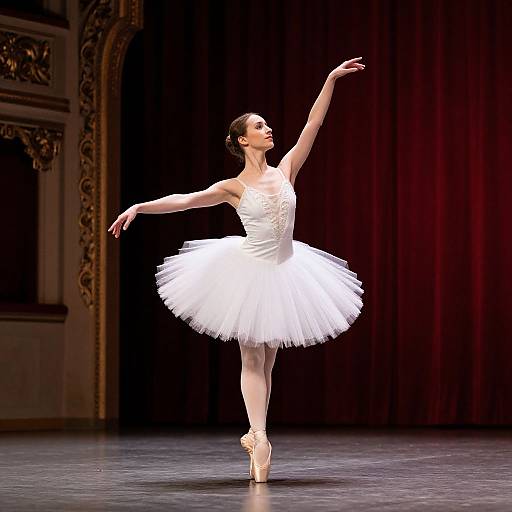 Photograph of a slender ballerina in a white tutu, en pointe, gracefully extending her arms and head on a stage with ornate