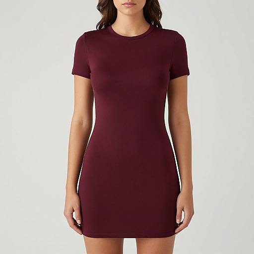 Photograph of a woman with wavy dark hair, wearing a tight, short-sleeved, maroon dress, standing against a plain white background