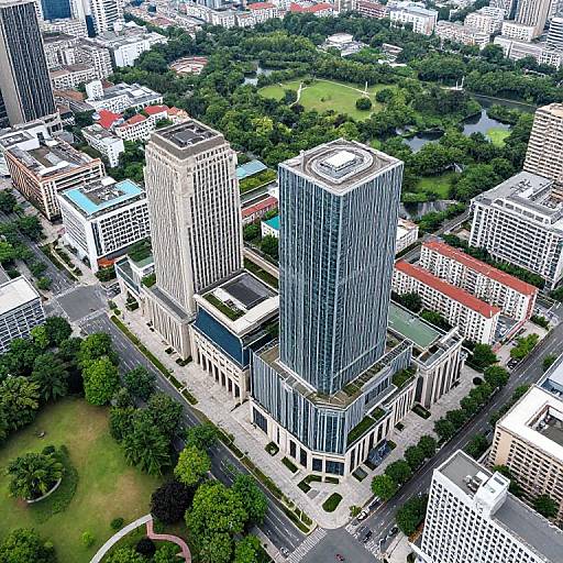 Aerial photograph of a dense urban landscape featuring tall, modern skyscrapers with reflective glass windows, surrounded by lush green parks and tree-lined streets.