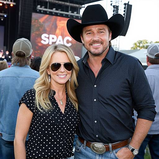 Photograph of a smiling couple at a Spac concert; man in black shirt, cowboy hat, and jeans, woman in black polka dot top
