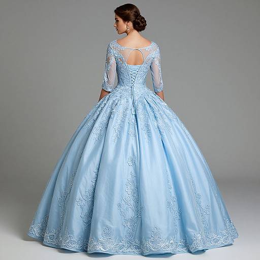 Photograph of a woman in a light blue, full-length, lace-embellished ball gown with three-quarter sleeves and a cut-out back,