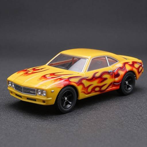 Photograph of a yellow muscle car with red-orange flame decals, black wheels, on a textured dark gray surface.