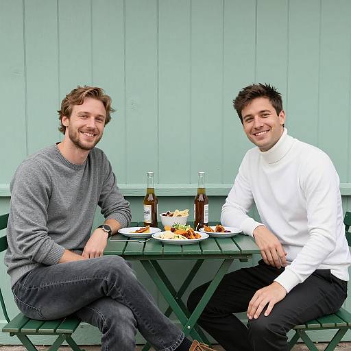 Two Men Sitting at Outdoor Table with Food and Beer