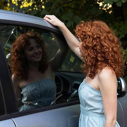 Woman with curly red hair beside broken car window