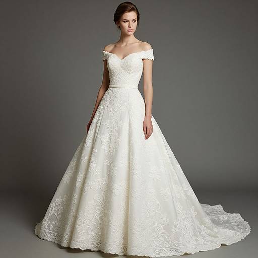 Photograph of a slender, fair-skinned woman in an off-shoulder, white lace wedding gown with a full, embroidered skirt, standing against