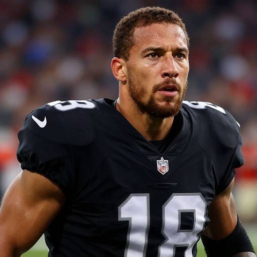 Photograph of muscular, bearded NFL player with short black hair, wearing black uniform #98, focused expression, sweat on face, blurred stadium background