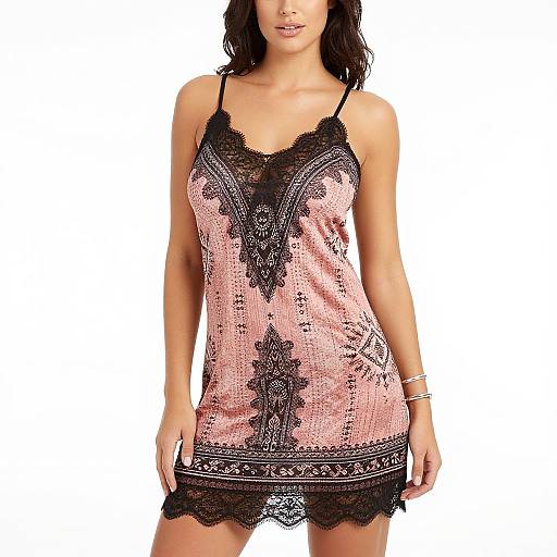 Photograph of a woman with dark wavy hair wearing a pink lace-trimmed babydoll nightie with black floral patterns and thin straps, standing