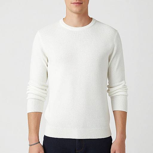 Photograph of a man from the neck down, wearing a plain white, ribbed, long-sleeve sweater and black pants, against a white
