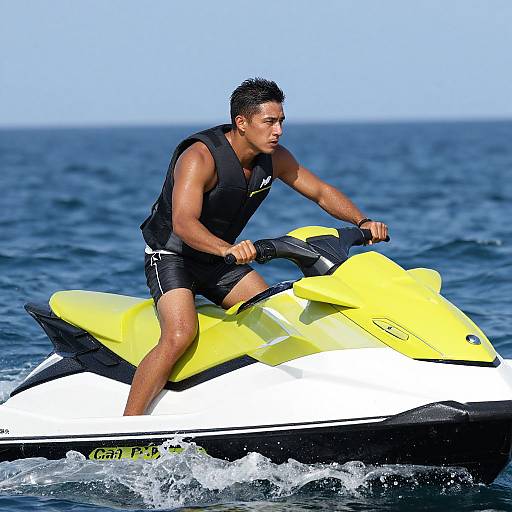 Photograph of a muscular, tan-skinned man with short black hair, wearing a black life vest and black swim trunks, riding a yellow and