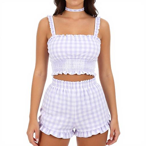Photograph of a woman wearing a white checkered, ruffled crop top and matching high-waisted shorts, with a white choker necklace.