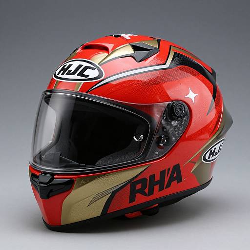 Photograph of a bright red, glossy, aerodynamic motorcycle helmet with black and gold accents, clear visor, 