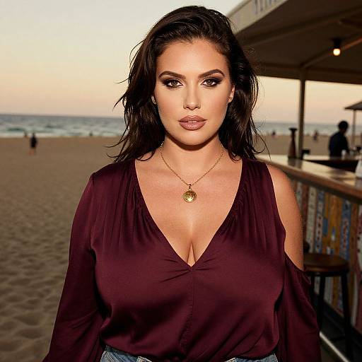 Photograph of a dark-haired woman with fair skin, wearing a deep V-neck maroon blouse and gold necklace, standing at a beachside bar with