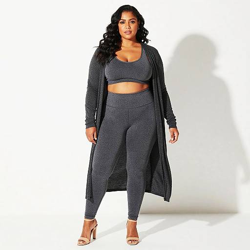 Photograph of a curvy woman with long black hair, wearing a gray crop top, matching high-waisted leggings, long cardigan, and