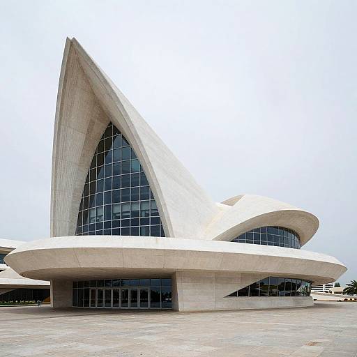 Photograph of the Sydney Opera House's iconic white concrete shells with large, curved, glass-paneled sections against a clear sky.