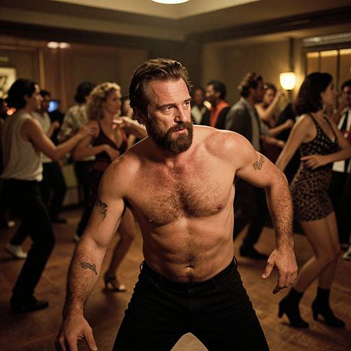 Photograph of a muscular, bearded, shirtless man with tattoos, dancing intensely in a dimly lit, crowded room with other partygoers