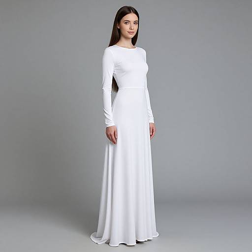 Photograph of a fair-skinned woman with long black hair wearing a long-sleeve, floor-length white dress against a plain gray background.