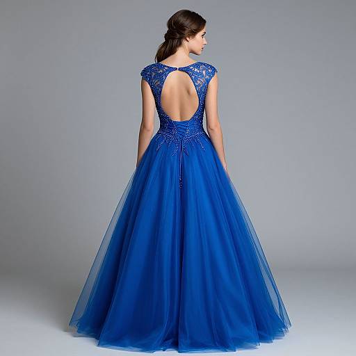 Photograph of a woman with dark hair in an elegant, backless, royal blue, lace-embellished ball gown with a wide, flowing