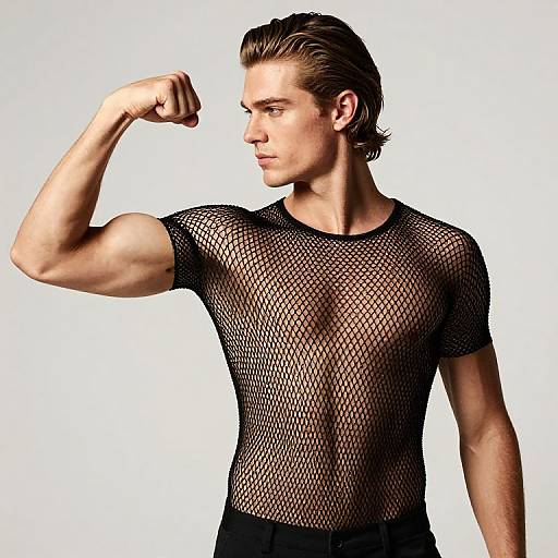 Photograph of a muscular, fair-skinned man with short brown hair, flexing his right arm, wearing a black fishnet shirt, against a